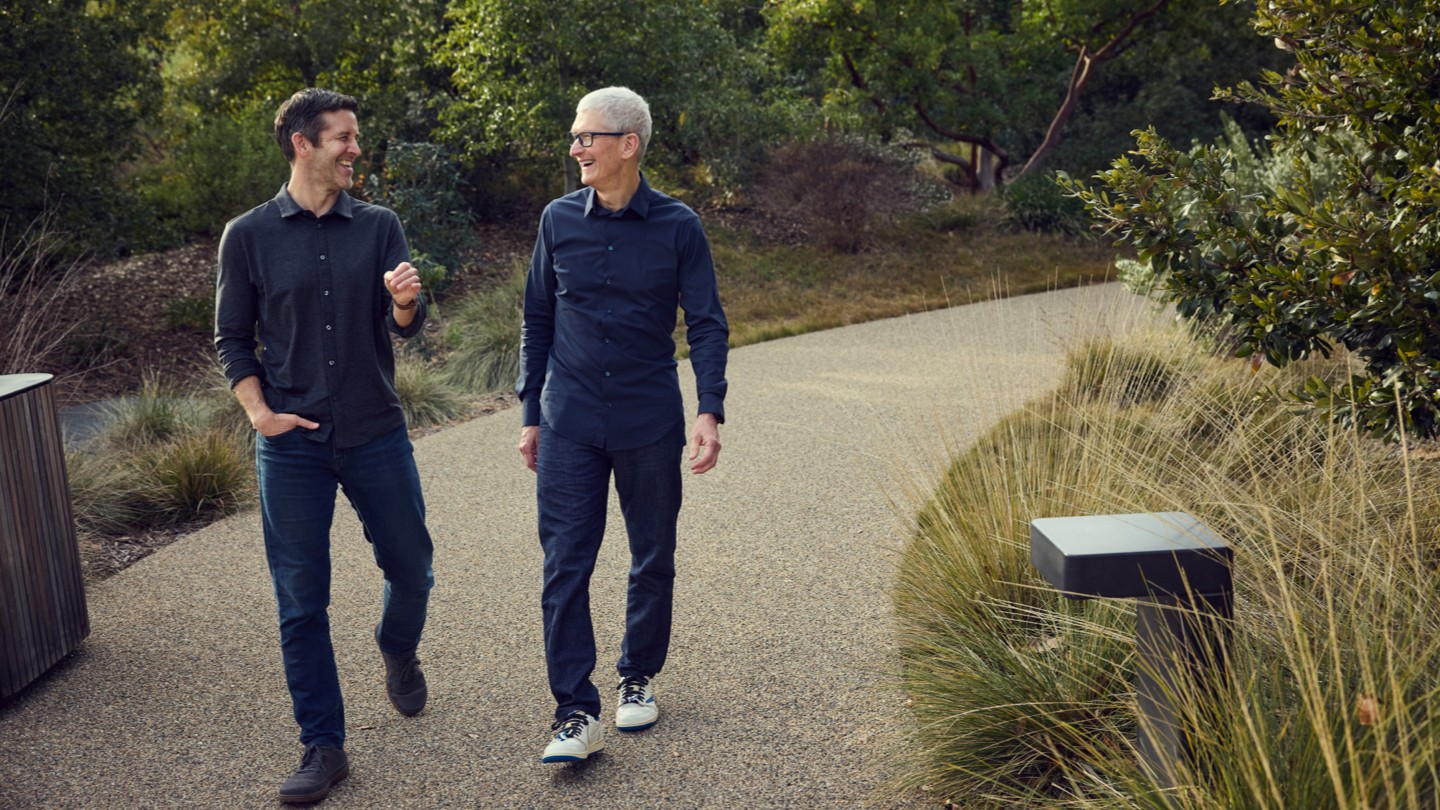 John Ternus and Tim Cook walking together on a path at Apple Park