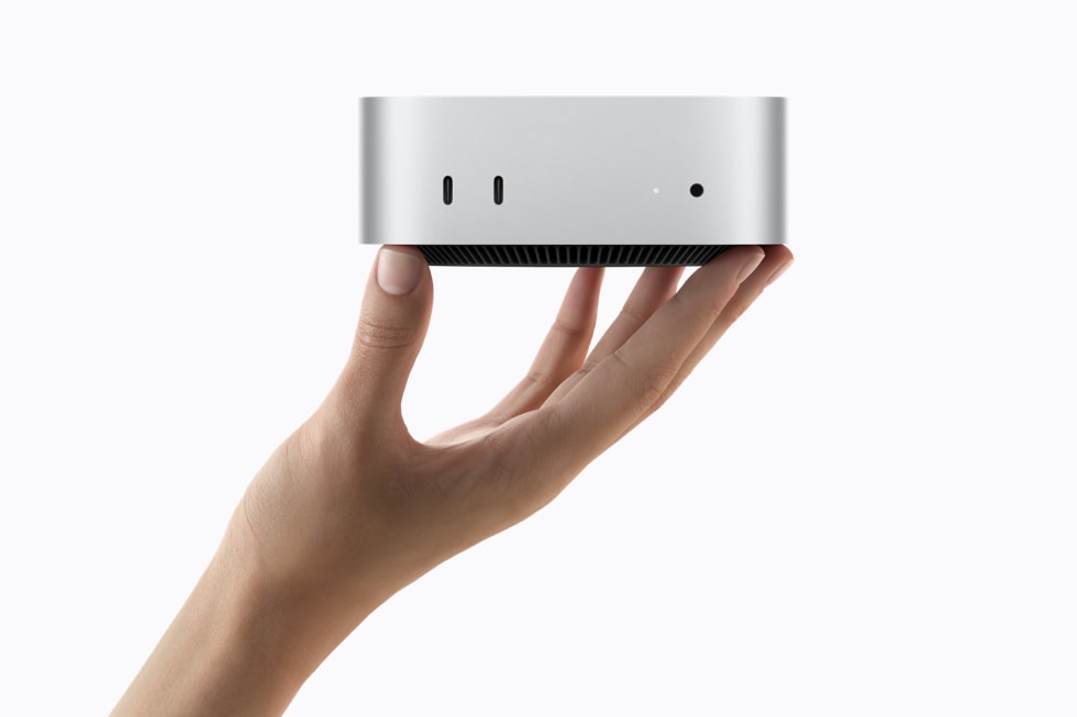 A hand holding the 2026 Mac mini, showing its two front USB-C ports